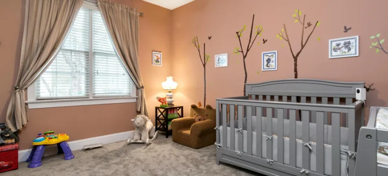 Barnrum med spjälsäng, dämpade färger och genomtänkt inredning som skapar en rofylld miljö för små barn