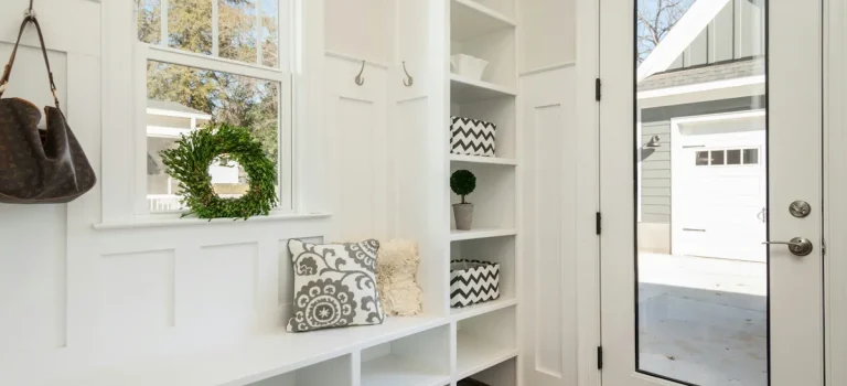 Inredning hall med inbyggd förvaring, bänk längs väggen, öppna hyllor, ljus färgskala och generöst dagsljus.